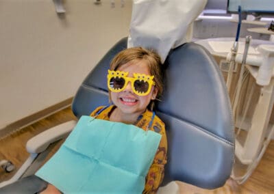 Child smiles big while seated in dental chair